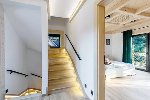 Pięknie oświetlone schody willi, w tle sypialnia